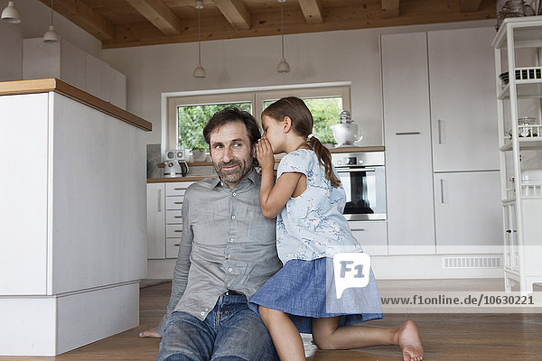 Father sitting on kitchen steps  daughter whispering into his ear