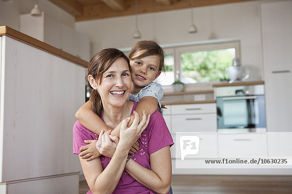 Mother and daughter sitting smiling in kitchen