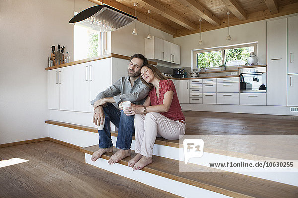 Mature couple sitting on floor  woman leaning head on man's shoulder