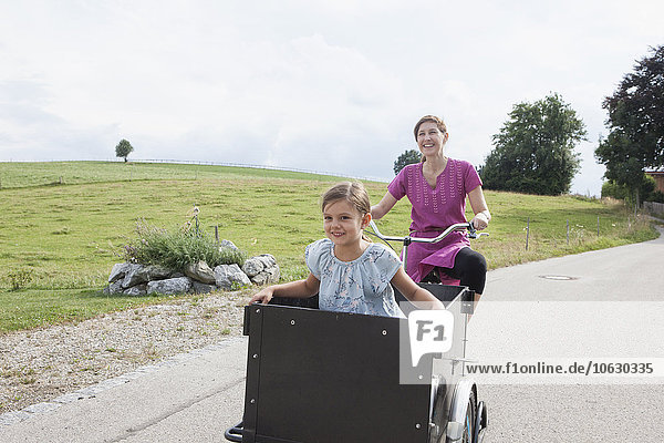 Fahrradmutter mit Tochter im Anhänger