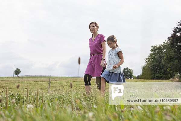 Mother walking with daughter on rural field