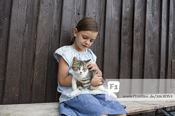 Mädchen mit Katze auf der Bank sitzend