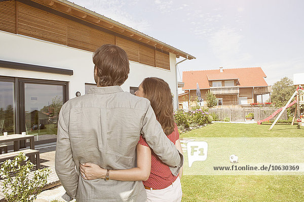 Couple standing in garden looking at house