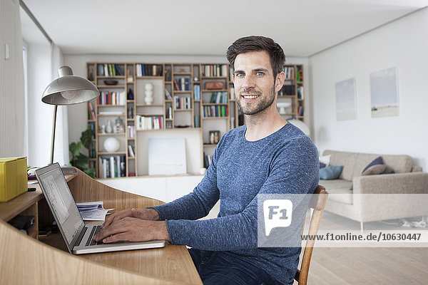 Portrait of smiling man at home using laptop