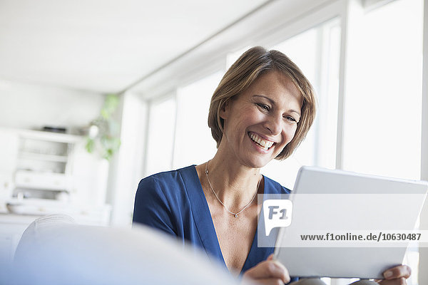 Lächelnde Frau zu Hause mit digitalem Tablett