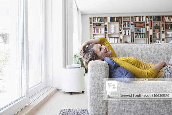 Happy woman at home lying on couch