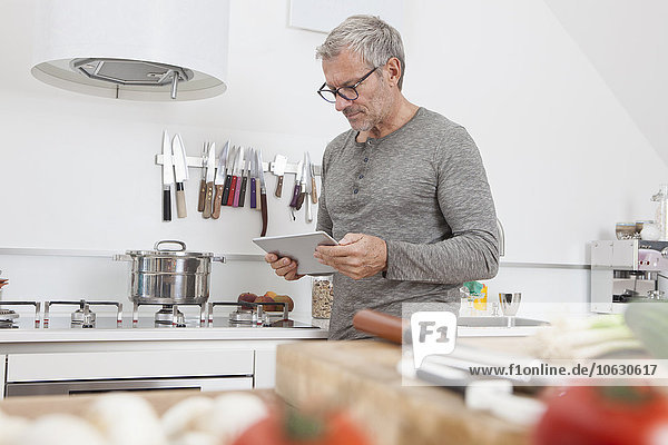 Mann mit digitalem Tablett in der Küche