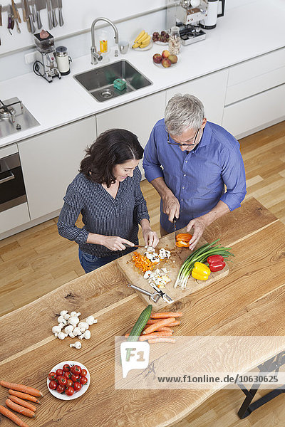 Reife Paare bereiten Gemüse in der Küche zu.