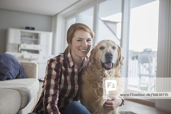 Porträt einer lächelnden jungen Frau mit ihrem Hund zu Hause