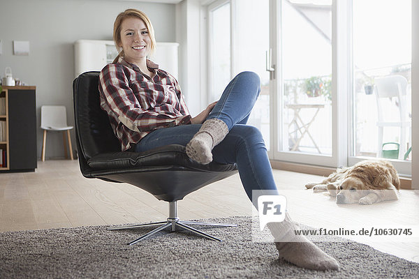 Portrait of smiling young woman relaxing on a leather armchair at home