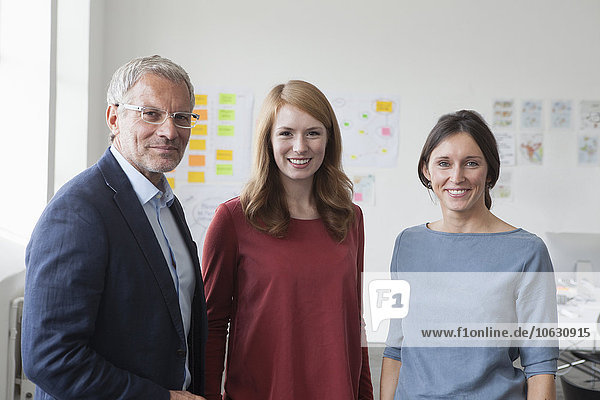 Porträt des lächelnden Geschäftsmannes und zweier Frauen im Amt