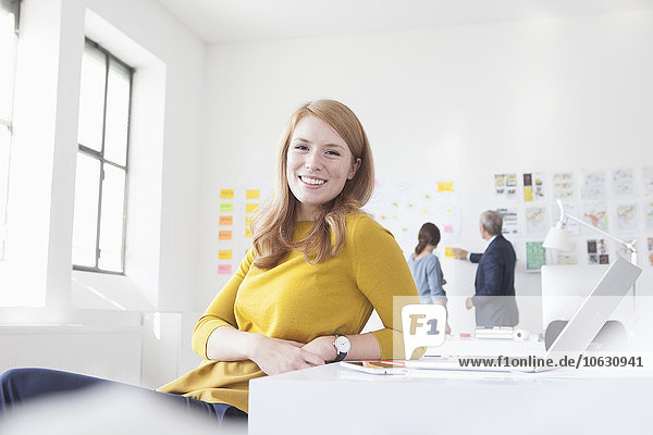 Smiling young woman in office at desk