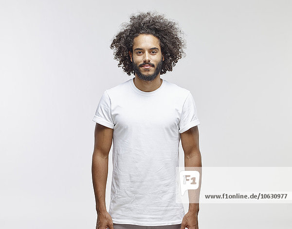 Portrait of bearded young man with curly brown hair wearing white t-shirt