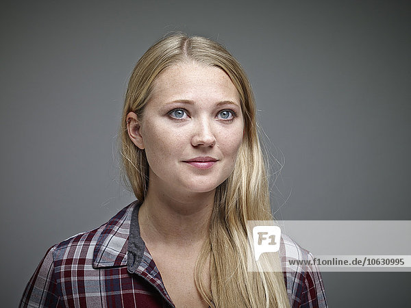 Porträt einer jungen blonden Frau vor grauem Hintergrund
