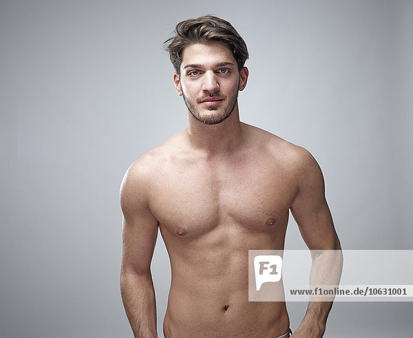 Porträt eines jungen Mannes ohne Hemd vor grauem Hintergrund