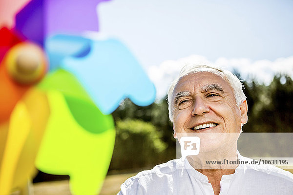 Lächelnder älterer Mann mit Windrad im Freien