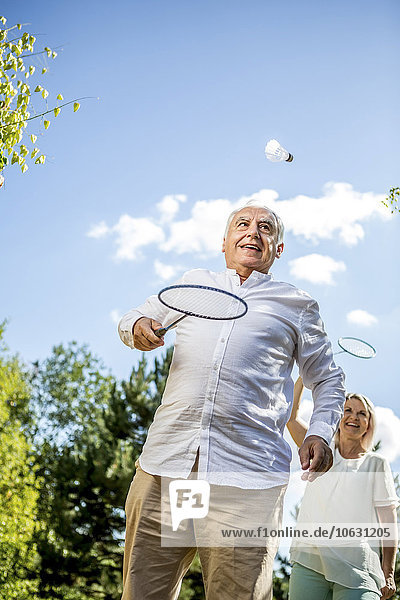 Happy elderly couple playing badminton outdoors