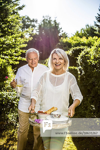 Älteres Paar mit Karaffe und Tablett im Garten