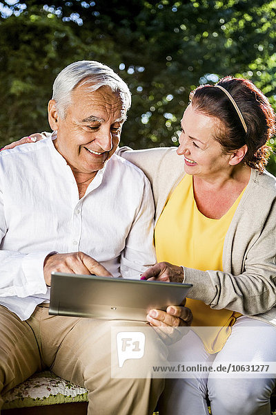 Happy elderly couple using digital tablet outdoors