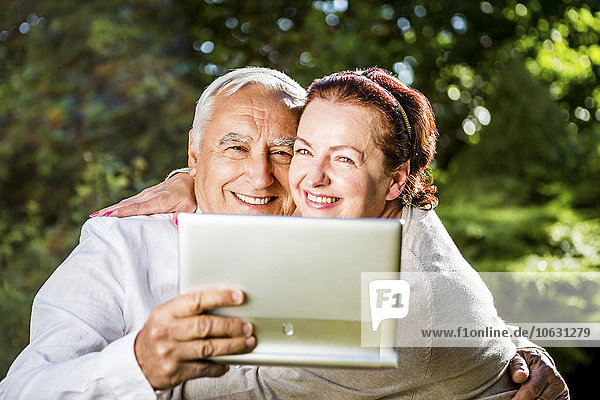 Glückliches älteres Paar mit digitalem Tablett im Freien