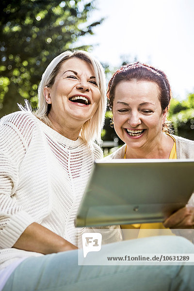 Glückliche reife Frauen im Garten mit digitalem Tablett