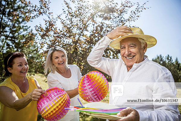 Portrait of happy elderly friends with lampions and straws outdoors