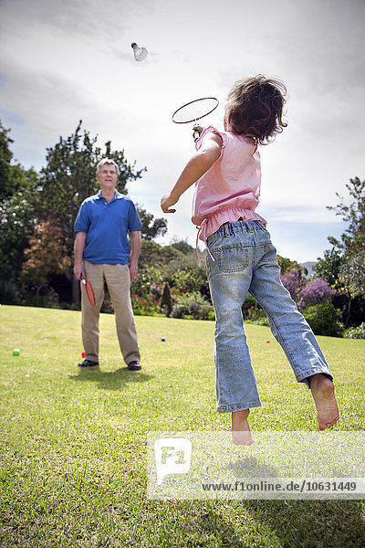 Little girl playing badminton with her grandfather