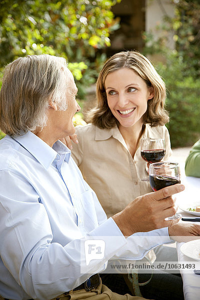 Two friends toasting with red wine in the garden