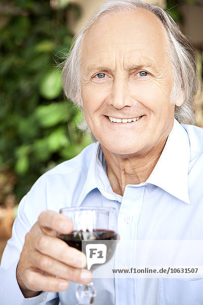Porträt eines entspannten älteren Mannes mit einem Glas Rotwein