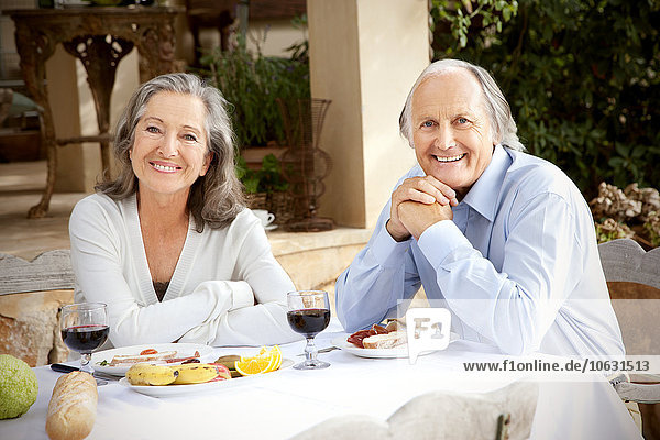 Spanien  Mallorca  glückliches Ehepaar am gedeckten Tisch im Garten