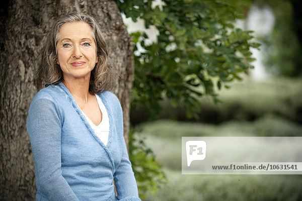 Spain  Mallorca  portrait of smiling mature woman in front of a tree in the garden