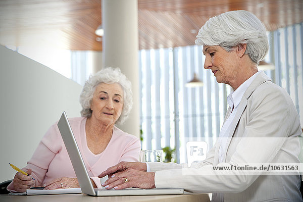Zwei ältere Frauen arbeiten zusammen am Laptop