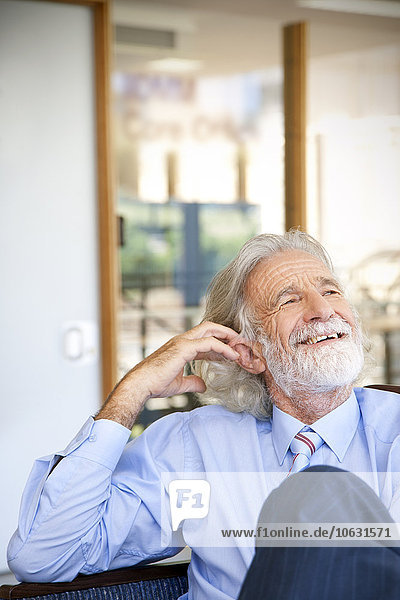 Laughing senior man sitting in chair  portrait