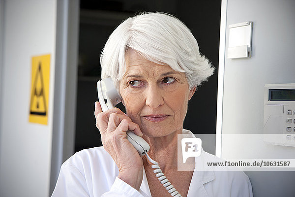 Senior woman working at laboratory making a call