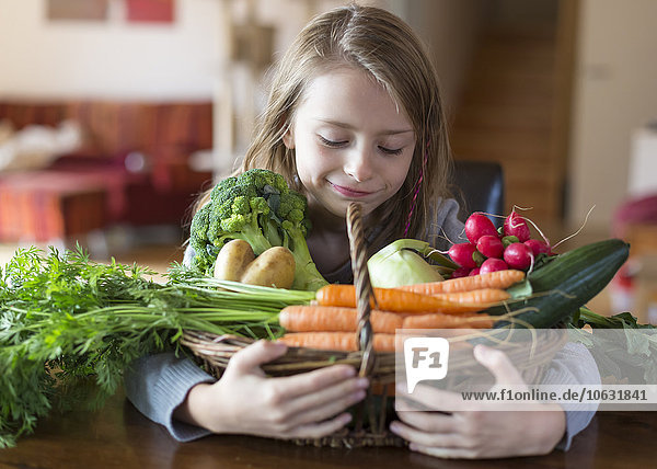Porträt des lächelnden Mädchens mit Korb mit frischem Gemüse zu Hause