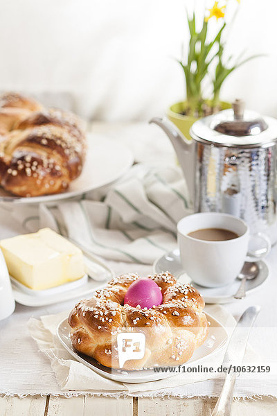 Geflochtenes Osterbrot mit rosa Ei  Narzisse  Kaffee und Butter