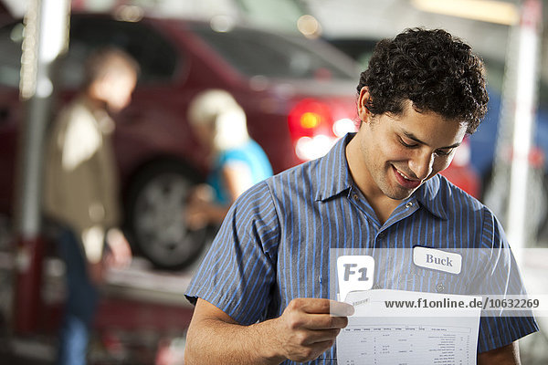 Smiling man in repair garage looking at ckeck list