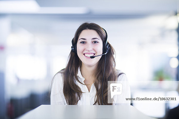 Porträt einer lächelnden jungen Frau mit Headset im Büro