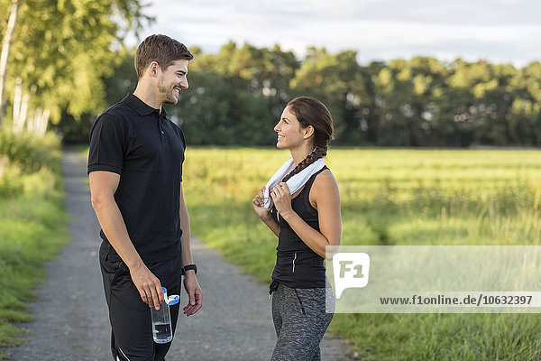 Sportlicher Mann und Frau im Gespräch auf dem Landweg
