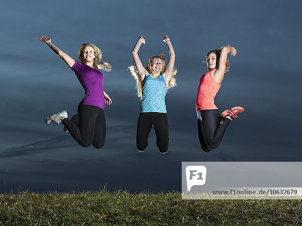 Drei junge Frauen,  die zusammen in die Luft springen.