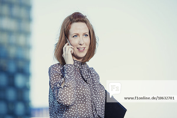 Portrait of redheaded businesswoman telephoning with smartphone