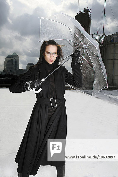 Deutschland  München  Porträt einer Frau in schwarzer Kleidung auf einem Dach mit transparentem Regenschirm