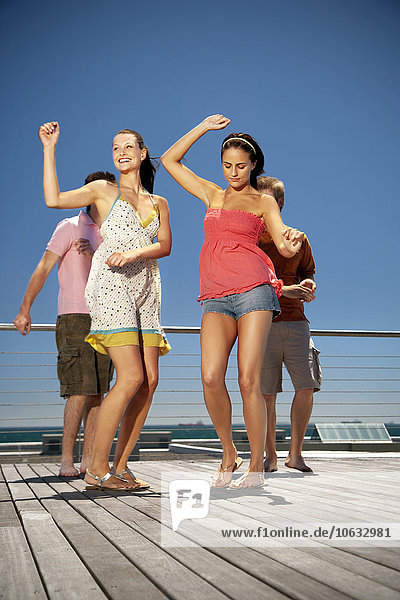 Happy friends dancing on wooden terrace