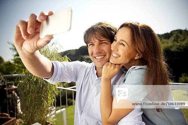 Glückliches Paar auf dem Balkon mit einem Selfie