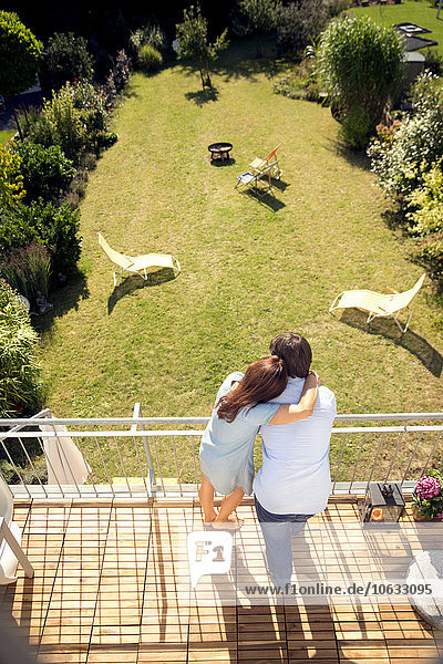 Couple embracing on balcony above garden