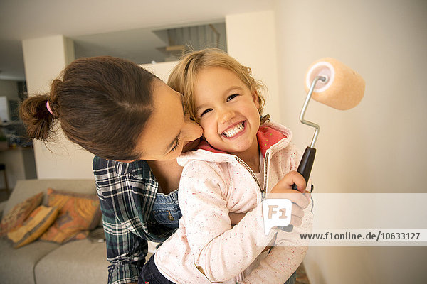Happy woman with daughter painting a wall
