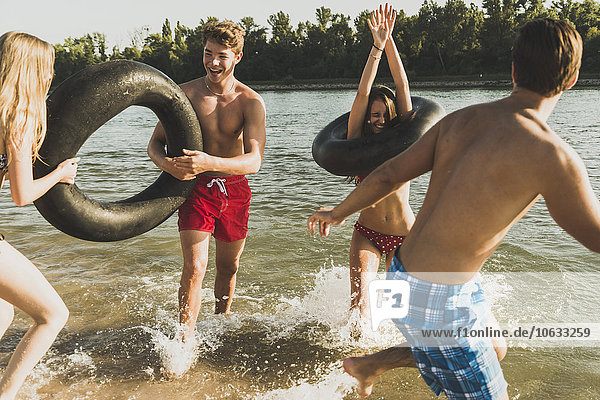 Playful friends with inner tubes in river