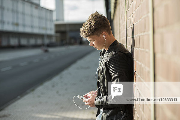 Young man wearing earbuds looking at cell phone