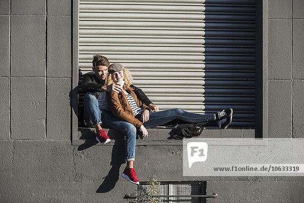 Entspanntes  junges Paar  das sich ein Handy im Freien teilt.