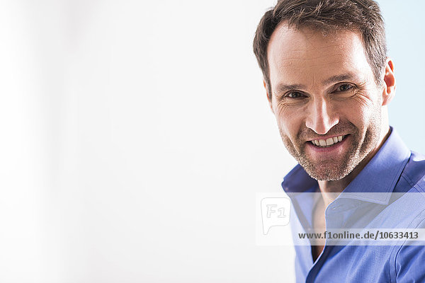 Porträt eines lächelnden Mannes mit Stoppel in blauem Hemd